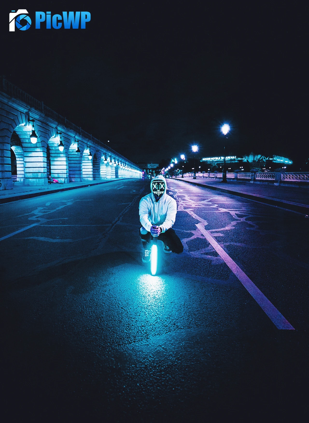 Man kneeling on a street holding a neon light 4K Mobile Wallpaper